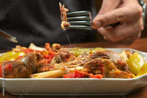 man eats lamb stew on the bone with vegetables. Khashlama is popular Armenian dish, which is prepared from beef with vegetables. Khashlama in the plate.  caucasian food photo