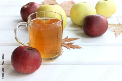 apple juice in a transparent mug on a table with autumn harvest of fruits. fresh vitamin drink