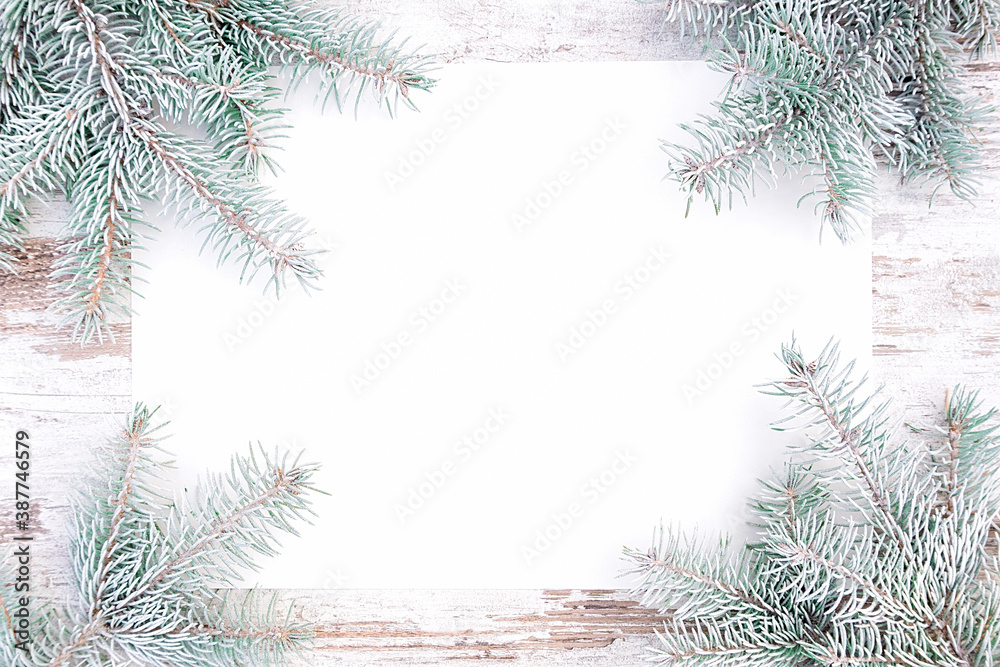 Nordic rustic style christmas background with snow covered spruce twigs and blank paper with copy space. Christmas design template on a light wooden background for greeting cards and invitations. Nordic rustic style christmas background with snow covered spruce twigs and blank paper with copy space. Christmas design template on a light wooden background for greeting cards and invitations.