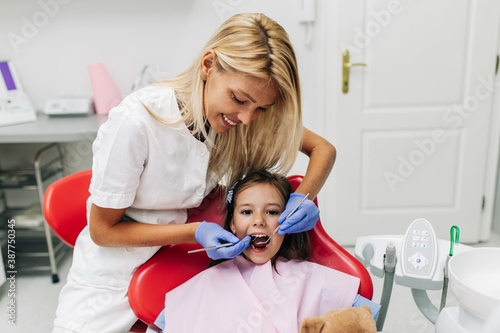 Fototapeta Naklejka Na Ścianę i Meble -  Cute little girl sitting on dental chair and having dental treatment.