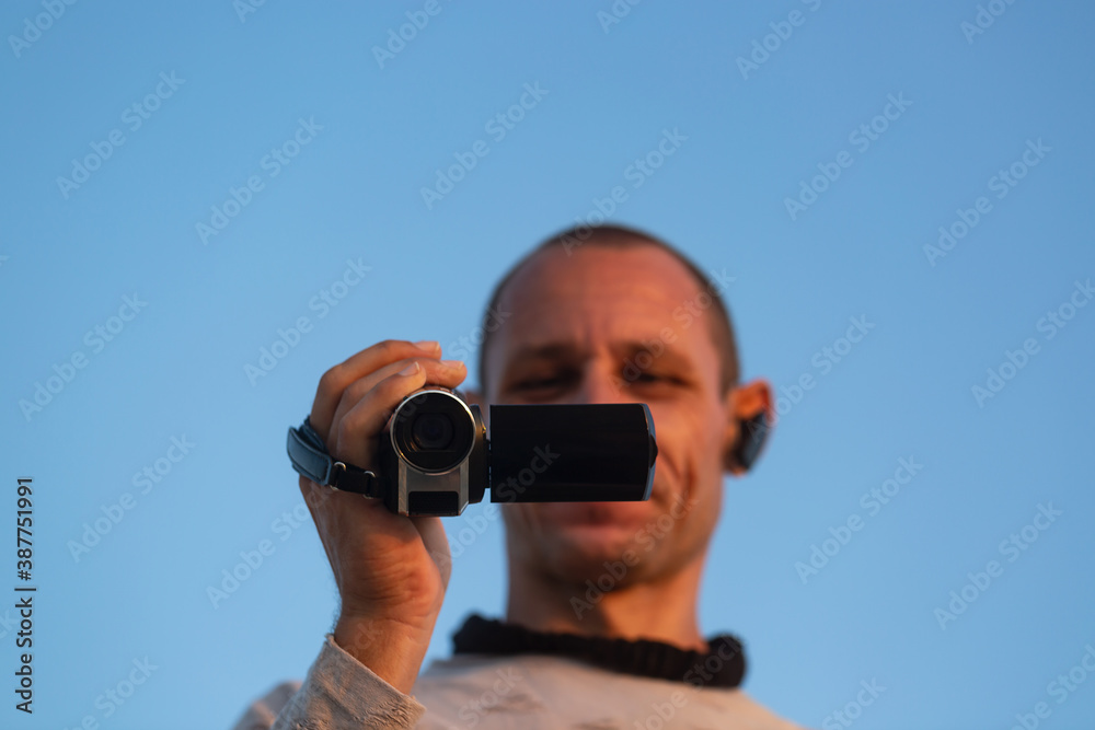 Obraz premium Professional videographer holding a camera. Focus on camera. Man hand holds digital black video camera