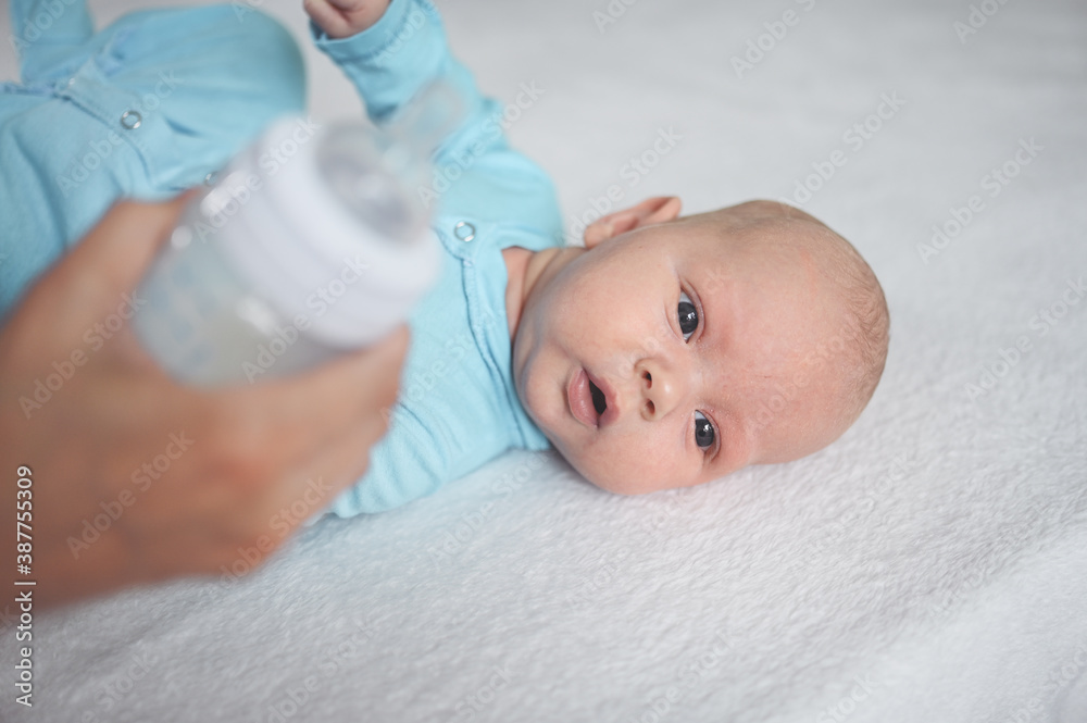 Cute emotional funny newborn infant boy laying on bed with milk bottle. Baby facial expressions. Cute emotional funny newborn infant boy laying on bed with milk bottle. Baby facial expressions.