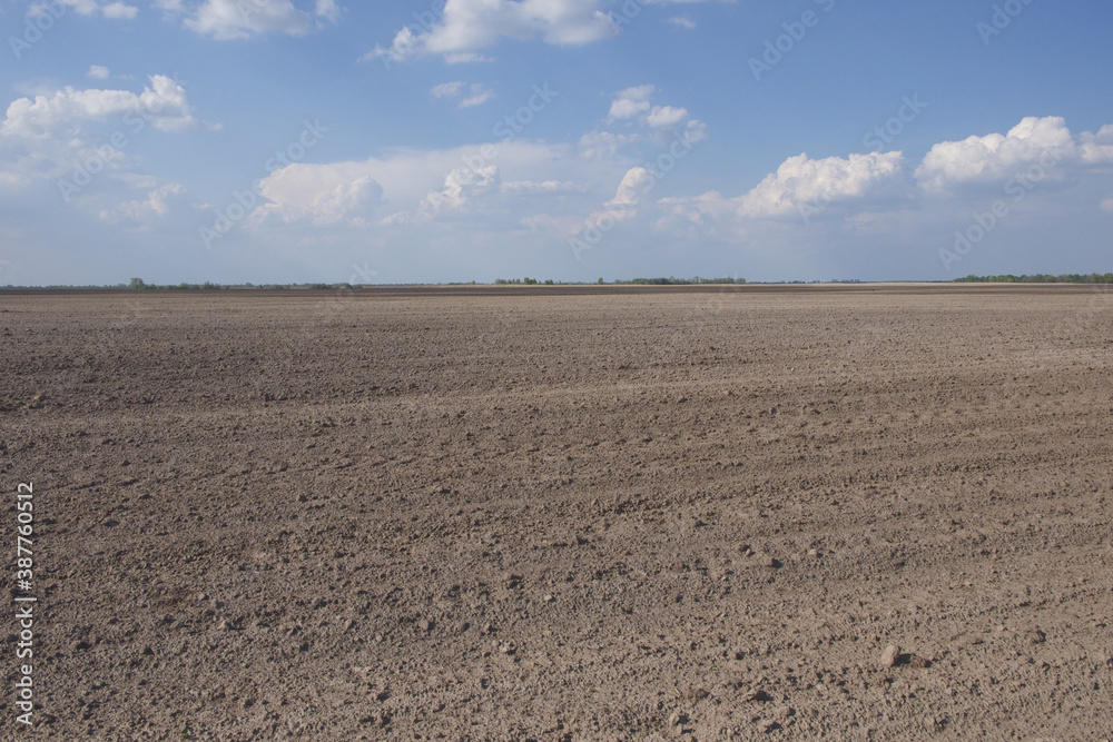 Beautiful sky over a plowed agricultural field. Agro-industrial landscape. A plowed farm field. Cultivated soil during the day. Beautiful sky over a plowed agricultural field. Agro-industrial landscape. A plowed farm field. Cultivated soil during the day.