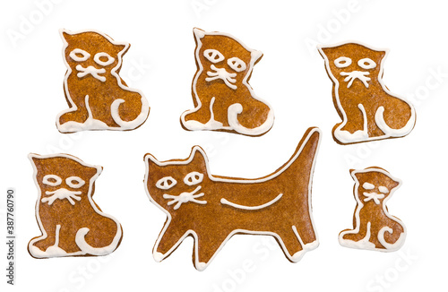 Set of cute baked cats of aromatic gingerbreads isolated on white background. Group of yummy cookies in cat or kitten shape painted with sweet frosting. Edible toys for Christmas or child celebration.