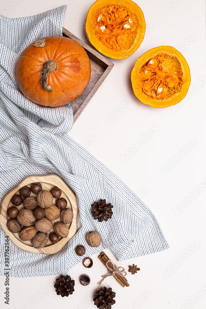 Still life with pumpkins whole and halves , nuts and cones on a light pink background. Autumn concept Still life with pumpkins whole and halves , nuts and cones on a light pink background. Autumn concept