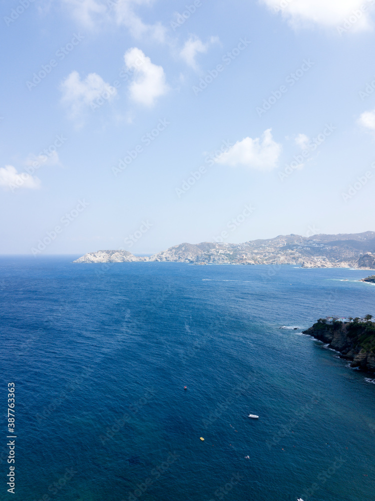 Aerial view of blue sea and mountains, rocky coast, blue sky, clouds, sunny day. Crete, Greece.