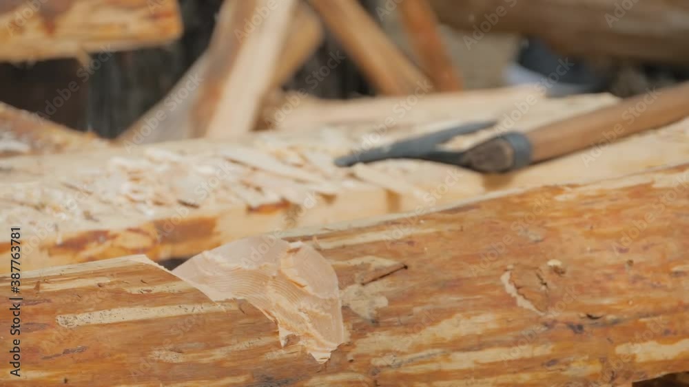 Slow motion: man lumberjack cutting large log with axe - wood shavings, chips flying at summer historical medival festival - close up. Craftsmanship, reenactment, handwork, revival concept Slow motion: man lumberjack cutting large log with axe - wood shavings, chips flying at summer historical medival festival - close up. Craftsmanship, reenactment, handwork, revival concept