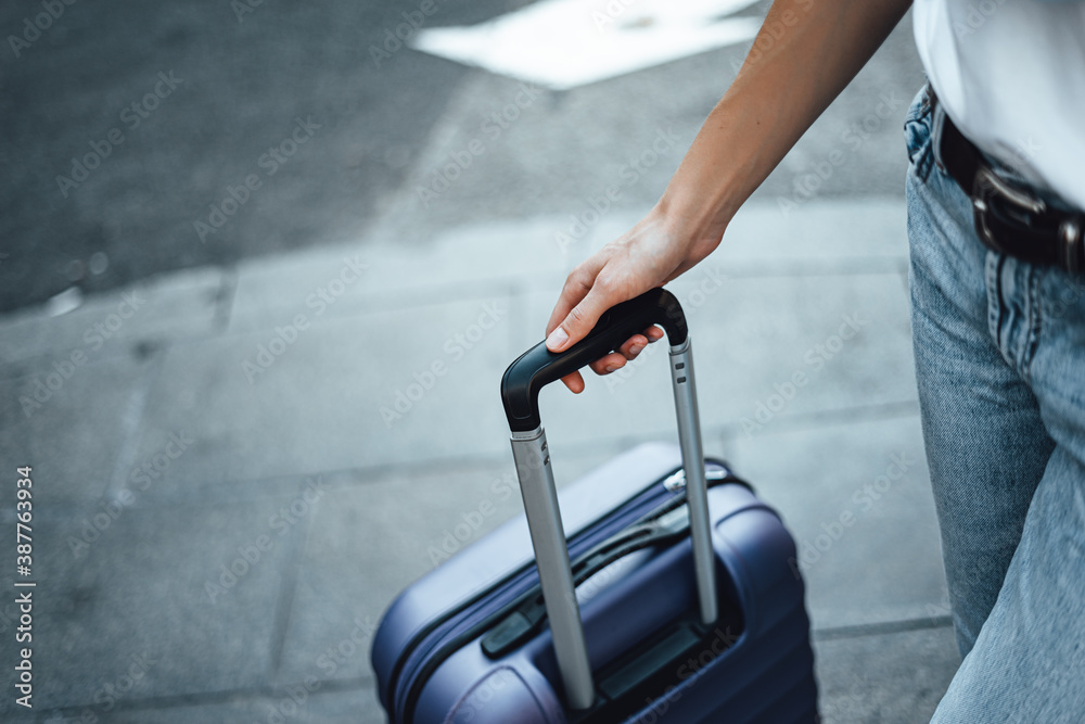 Close-up of a female hand holding suitcase. Young traveling woman with  luggage on a city street. Traveler on vacation. Stock-Foto | Adobe Stock
