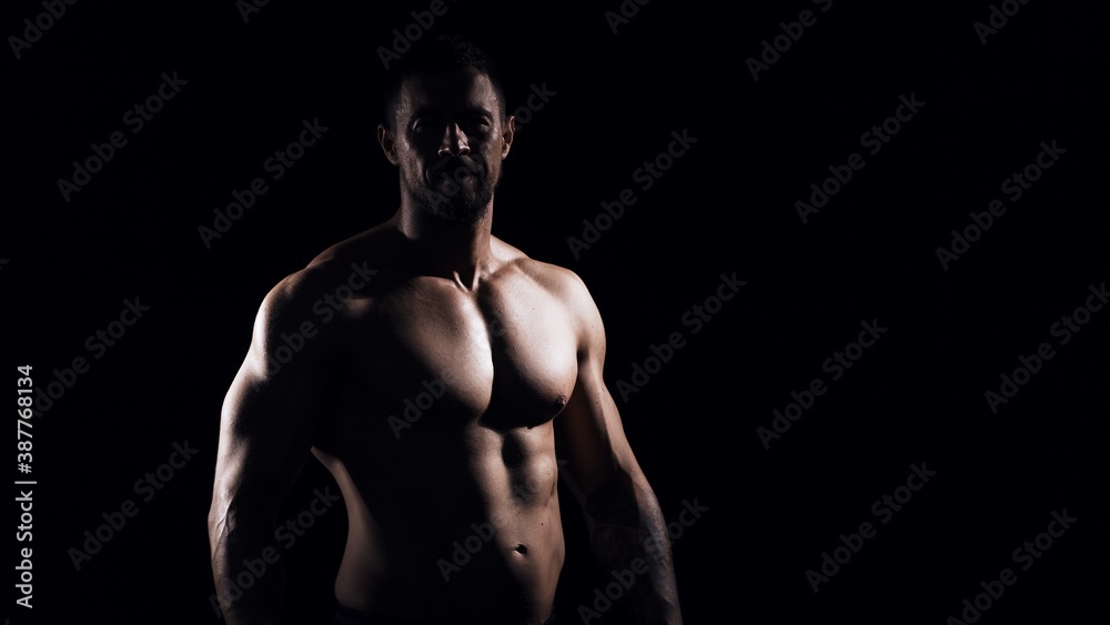 Fototapeta premium Fit and sporty bodybuilder over black background. Sportsman in studio. Sport and fitness concepts.