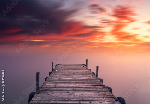 Dramatic sunset sky and silky water in long exposure, on a jetty of Albufera lake, in Valencia, Spain