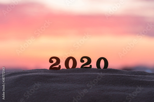 Silhouette of 2020 wooden numbers on the sand on the beach at sunset. Setting sun. The symbol of the outgoing year. 2021