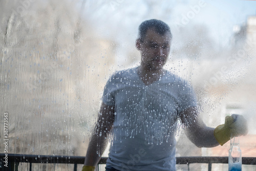 A man sprays detergent on the window glass. washing Windows. Spring cleaning of the house.