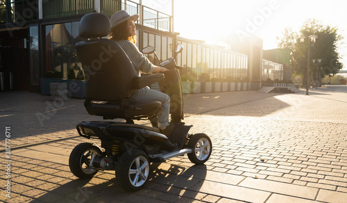 Woman tourist riding a four wheel mobility electric scooter on a city street.	 photo