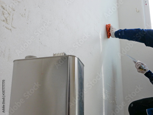 A hand of a painter holding on a piece of cloth, soaked with thinner, removing sticky rough glue and tape remain on the old concrete wall, as a preparation before starting the paint the house photo