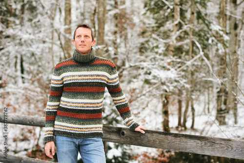 Outdoor winter portrait of middle age man in snowy forest, wearing warm knitted pullover © annanahabed