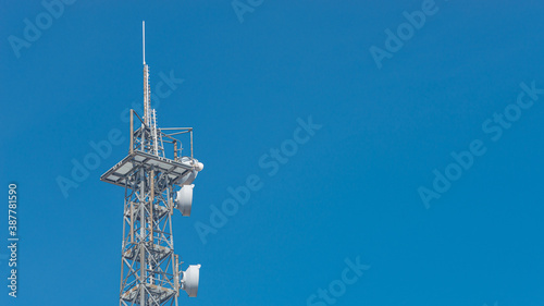 Fotografering Banner with telecommunication tower with many transmitters and receivers for various radio frequencies and data transmission, including 5G and satellite at blue sky