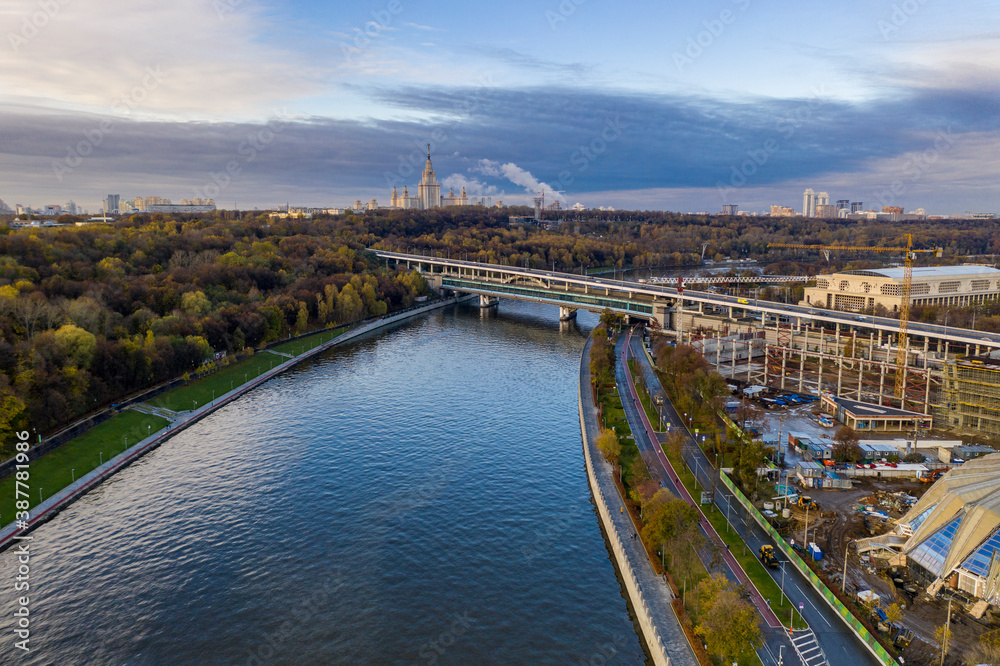 Fototapeta premium cityscape at sunrise on autumn morning with old houses, highways and river shot from drone