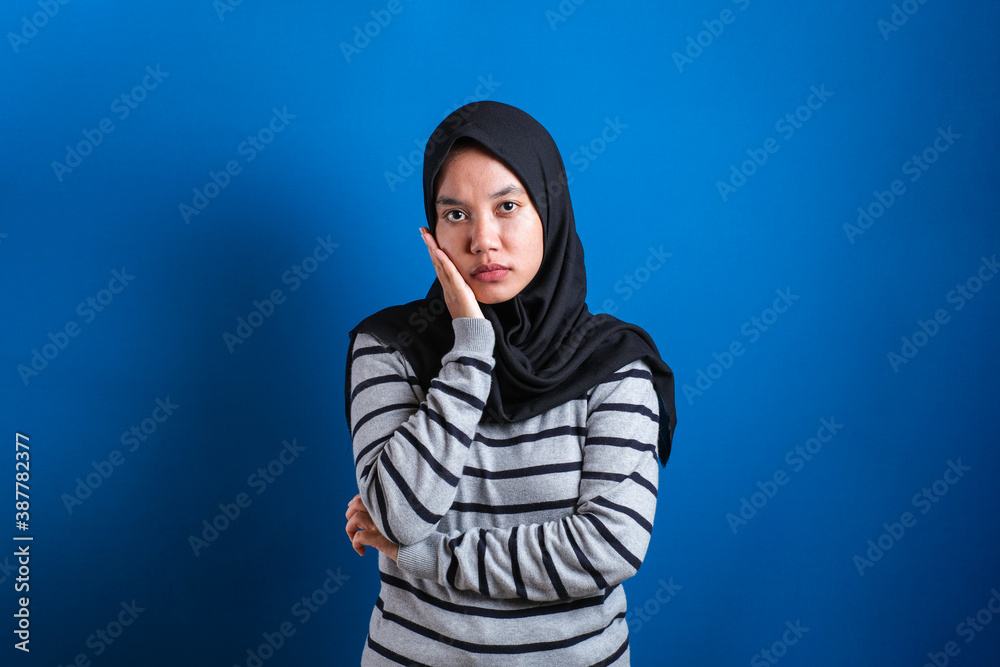 Portrait of angry cynical Asian muslim woman with suspicious expression Portrait of angry cynical Asian muslim woman with suspicious expression
