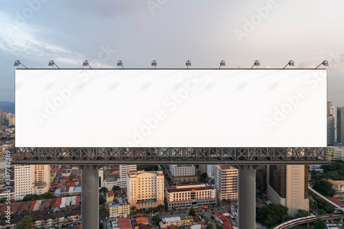 Blank white road billboard with Kuala Lumpur cityscape background at sunset. Street advertising poster, mock up, 3D rendering. Front view.