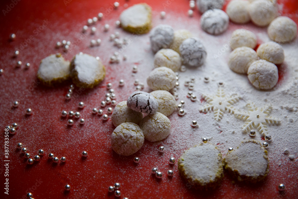 Handmade cookies, decorative snowflakes, decorative pearls and powdered sugar on the table. White on red. Handmade cookies, decorative snowflakes, decorative pearls and powdered sugar on the table. White on red.