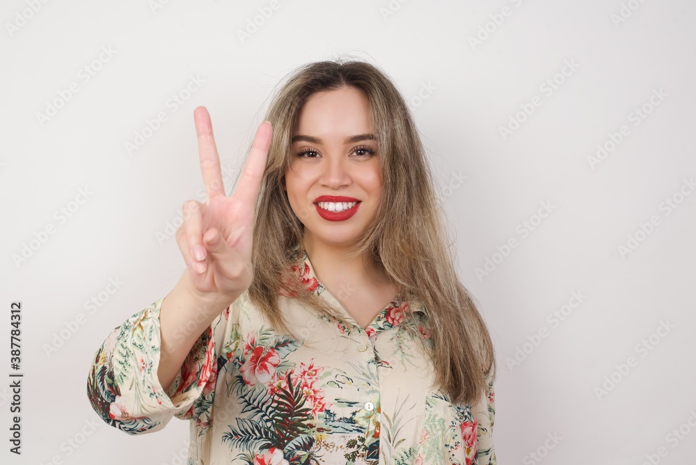 Young caucasian woman standing against gray wall showing and pointing up with fingers number two while smiling confident and happy. Young caucasian woman standing against gray wall showing and pointing up with fingers number two while smiling confident and happy.