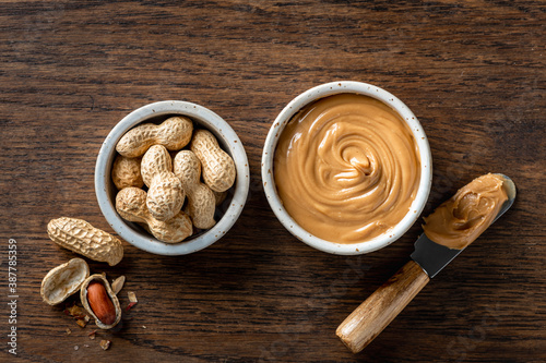 peanut butter in a ceramic bowl on wooden background, top view