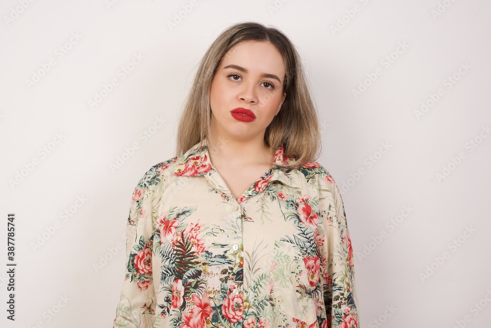 Gloomy, bored girl frowns face looking up, being upset with so much talking hands down, feels tired and wants to leave. Angry sullen woman standing indoors. Gloomy, bored girl frowns face looking up, being upset with so much talking hands down, feels tired and wants to leave. Angry sullen woman standing indoors.