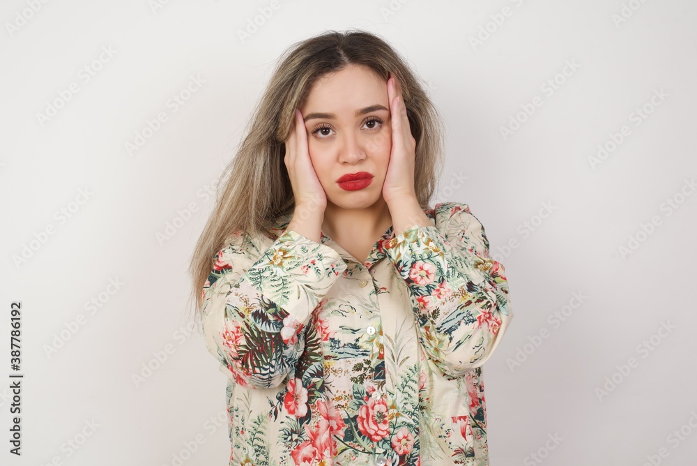 Portrait of beautiful young woman holding head in hands with unhappy expression watching sad movie about animals and trying not to cry. Portrait of beautiful young woman holding head in hands with unhappy expression watching sad movie about animals and trying not to cry.