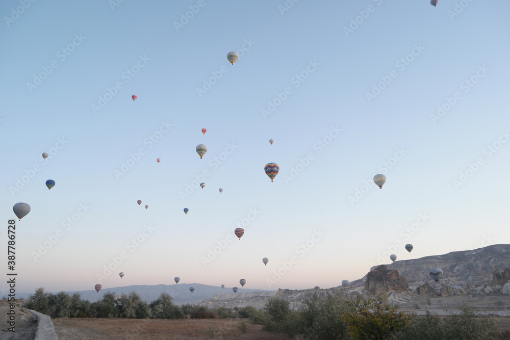 Panoramic view of hot air balloons flying over mountains. Ballooning at Goreme National Park. Cappadocia, Turkey.