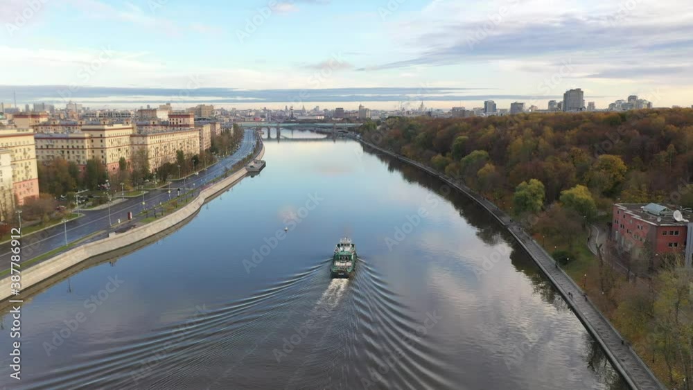 a panoramic view of the river with a barge sailing along it in the center of a big city filmed from a drone a panoramic view of the river with a barge sailing along it in the center of a big city filmed from a drone