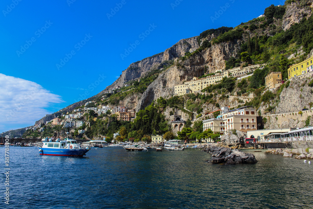 View of the town of Amalfi from the jetty with, the sea, boats and colorful houses on the slopes of the Amalfi coast in the province of Salerno, Campania, Italy.