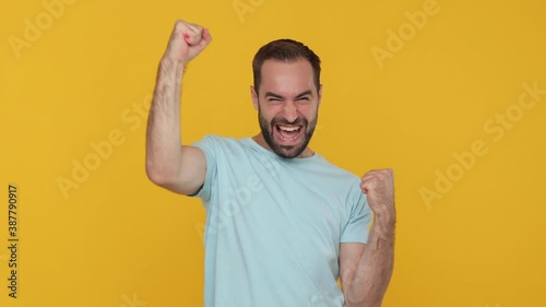 Fun young man 20s in basic casual blue t-shirt isolated on yellow background studio. People lifestyle concept. Look at camera count countdown 1 2 3 one two three go celebrating doing win hands gesture