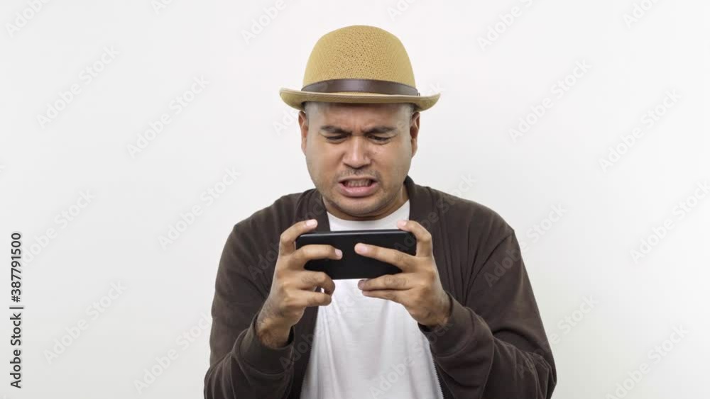 Guy put on hat in casual clothes using play mobile cell phone gadget pc smartphone for video games get loser isolated on white background. 4K Resolution. Guy put on hat in casual clothes using play mobile cell phone gadget pc smartphone for video games get loser isolated on white background. 4K Resolution.