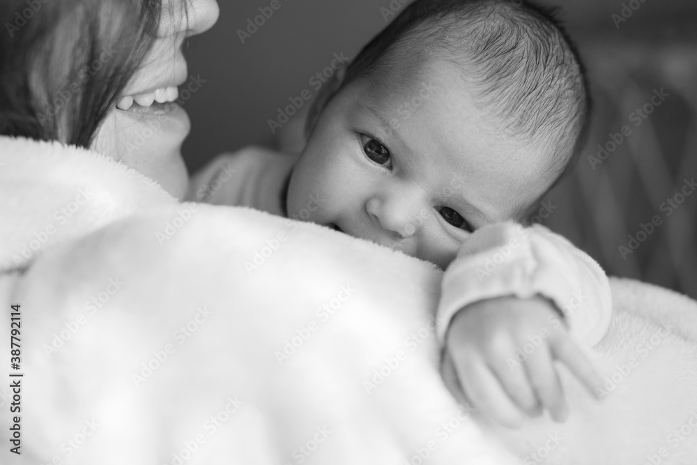 Loving mom carying of her newborn baby at home. Woman holds and hugs her child. Family morning at home. Black and white photo. Loving mom carying of her newborn baby at home. Woman holds and hugs her child. Family morning at home. Black and white photo.