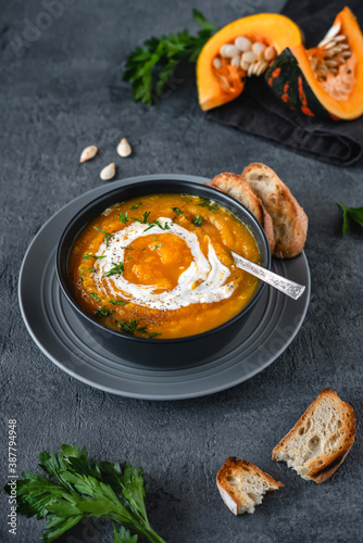 Pumpkin soup with ingredients on dark background. Vegetarian autumn pumpkin cream soup with croutons.