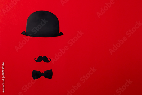 Stand of cardboard props mustache, hats, glasses, on a background of red textured paper. holiday kit, gentleman.