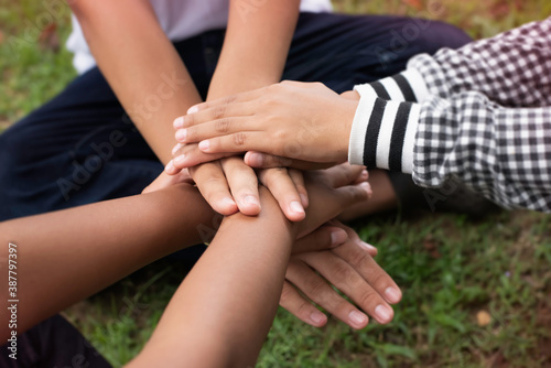 In selective focus of young children hands stacked together,friendship,collaborator,unity,sign of success and power,blurry light around