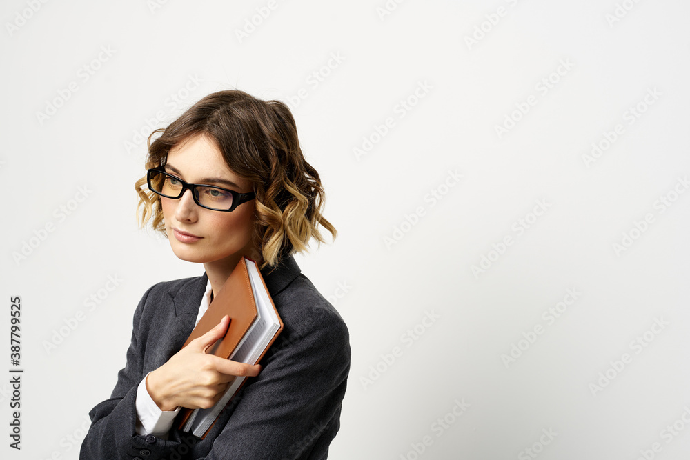 Woman at work with book in hand light background classic suit glasses head Woman at work with book in hand light background classic suit glasses head