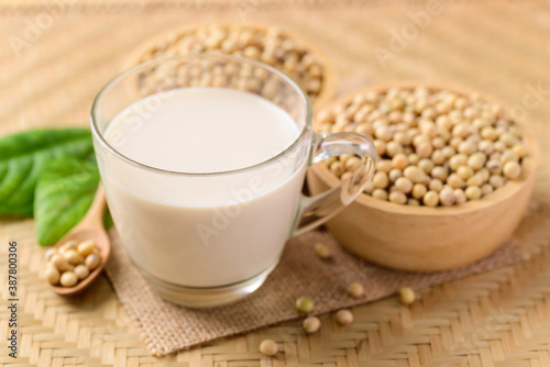 Soy milk in the glass and soy beans on wooden background