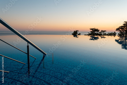 Entry of endless swimming pool with calm water and nobody in it during magnificent sunset 