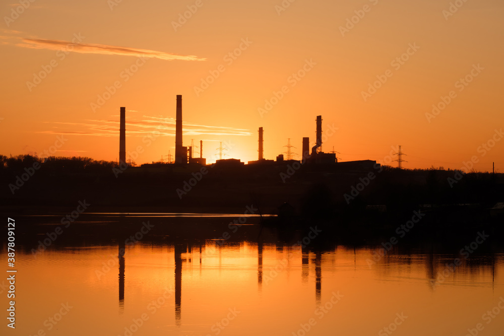 silhouette of factory chimneys on the other side of the river during sunset silhouette of factory chimneys on the other side of the river during sunset