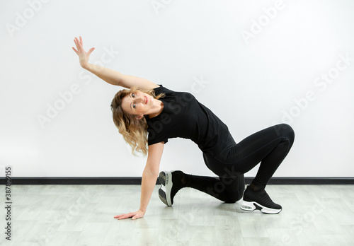 girl in sportswear is engaged in home fitness and posing against the wall. online sports. recovery after childbirth.