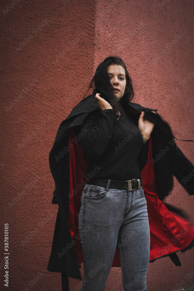 Naklejka premium A girl in a black cloak on a red background.