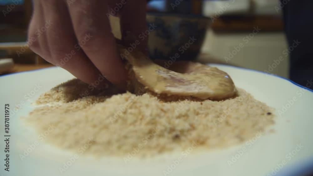 Hand dips schnitzel meat in flour bowl for cooking, close-up Hand dips schnitzel meat in flour bowl for cooking, close-up