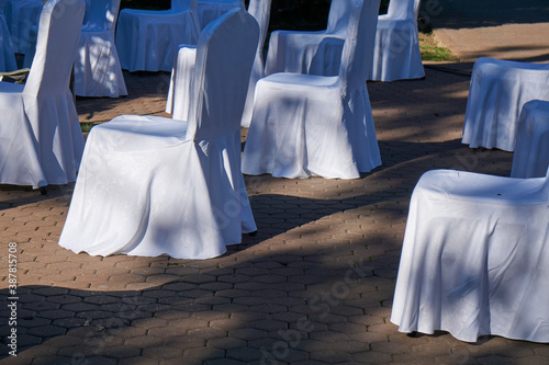 Large group of empty white chairs arranged for social distance, ready to sit visitors to outdoor business conference. COVID-19 health and safety measures during pandemic require spacing between people photo