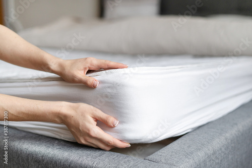 Woman putting new orthopedic mattress on sleeping bed