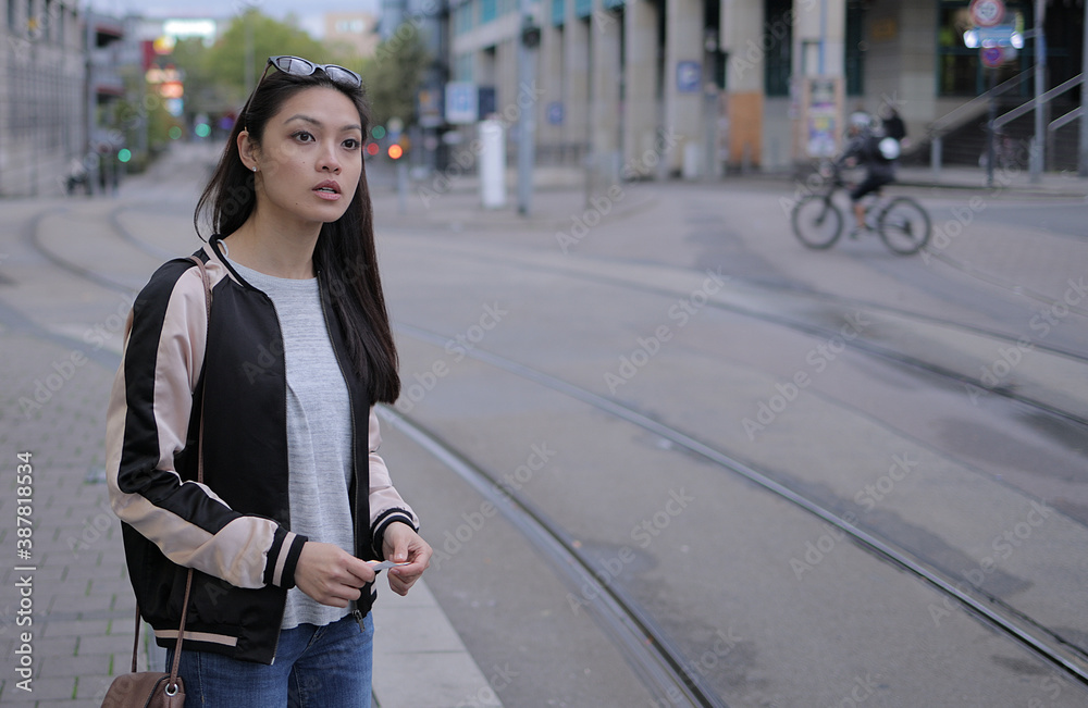 Fototapeta premium Young Asian woman waits for the tram in the city - urban photography