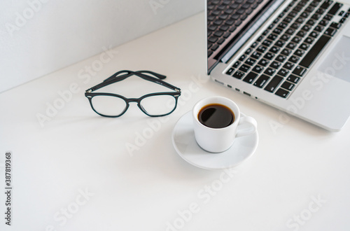 there is a mug of coffee and glasses on the table next to the laptop