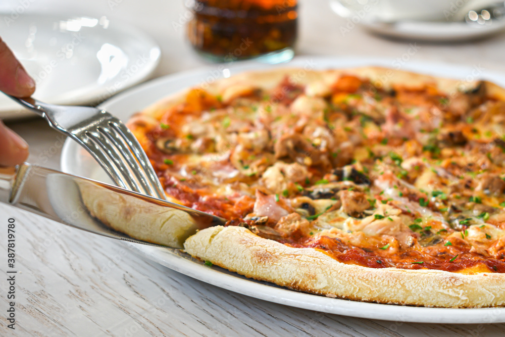 custom made wallpaper toronto digitalHands with a knife and fork cut a slice of pizza. Fresh pizza on a white dish, restaurant interior. Italian traditional cuisine. Delicious slice of pizza. The person wants to eat.