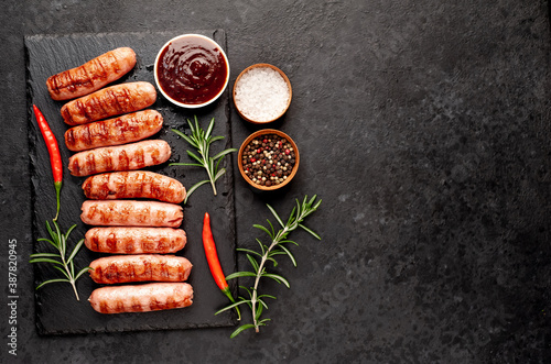 classic grilled sausages and sauce on a stone background with copy space